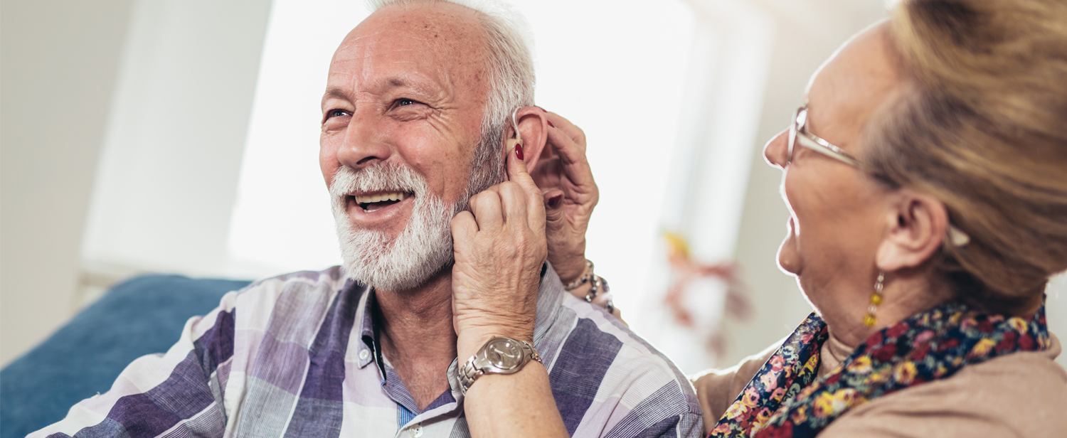 Smiling Man receiving a hearing aid
