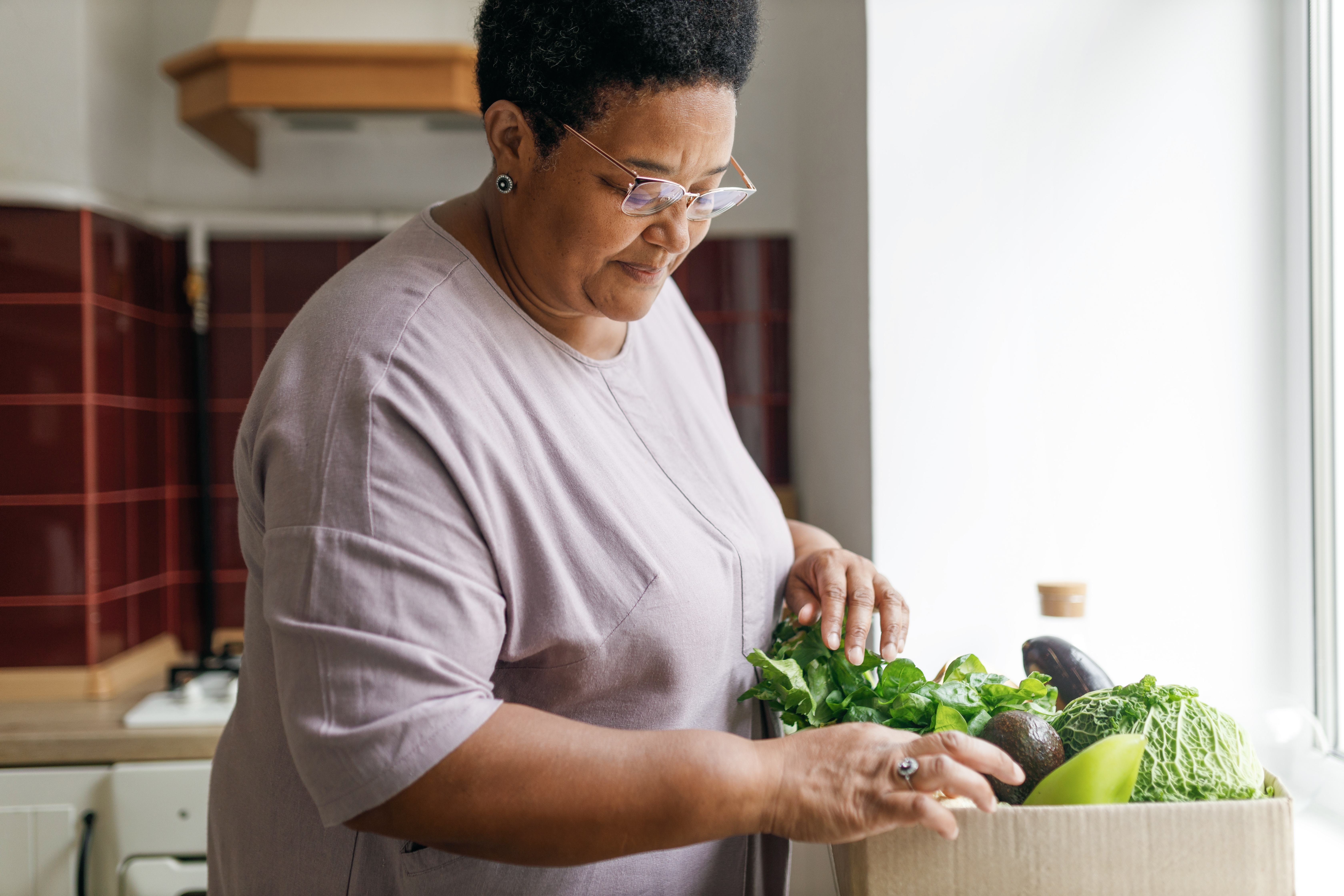 A woman unloads fresh groceries in her kitchen.