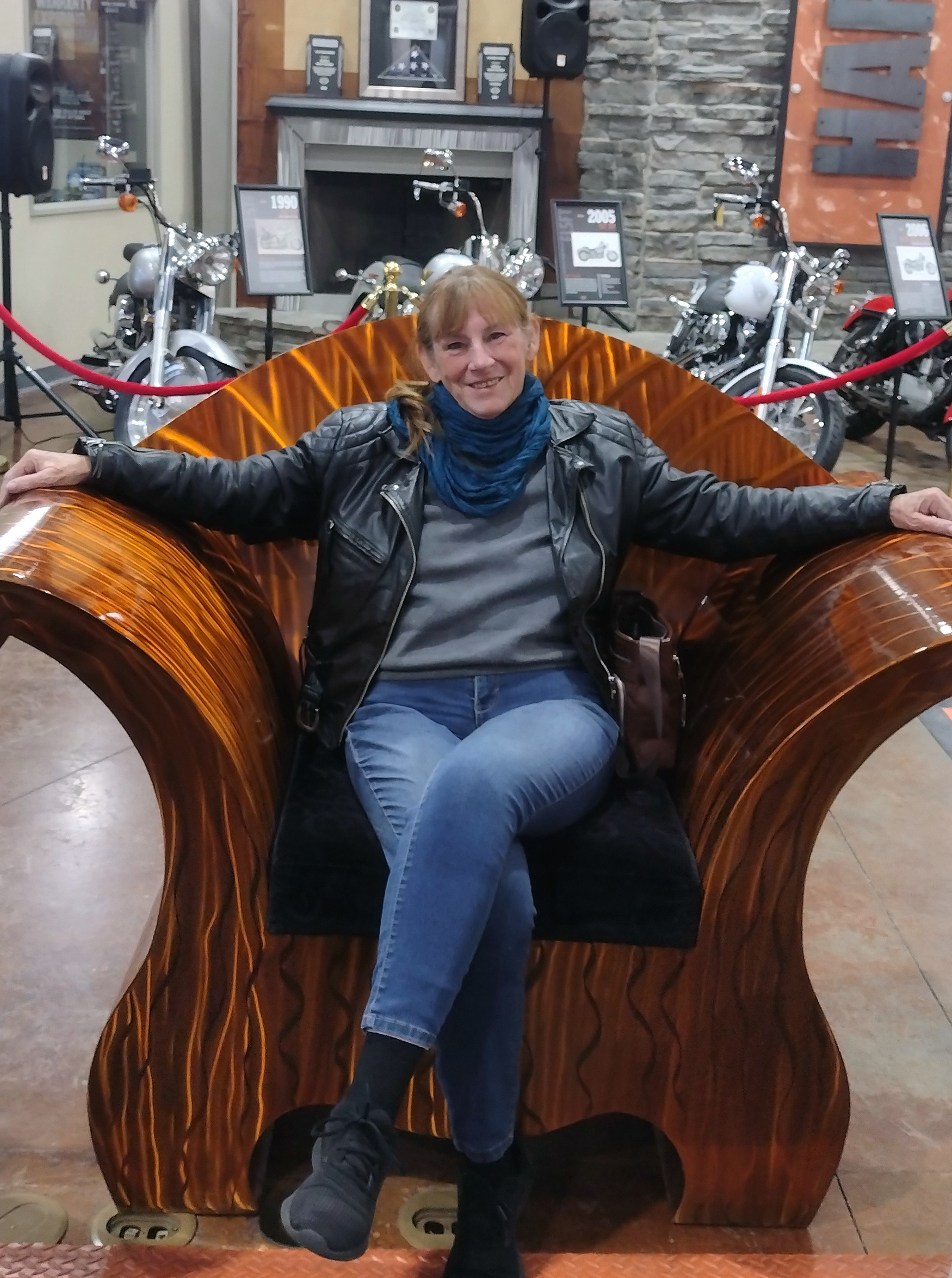 Senior woman sits on a large decorative chair.